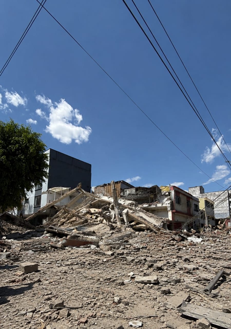 Calle cubierta de escombros junto a un edificio derrumbado tras el terremoto.